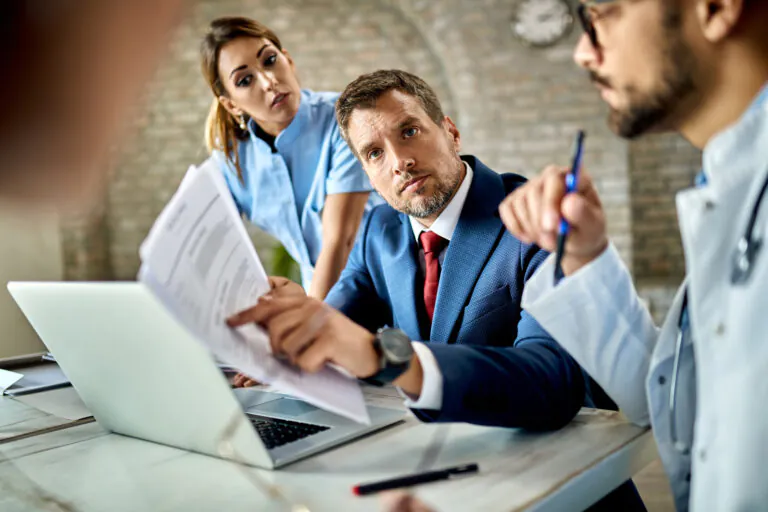 2mid adult businessman group doctors analyzing paperwork while having meeting office